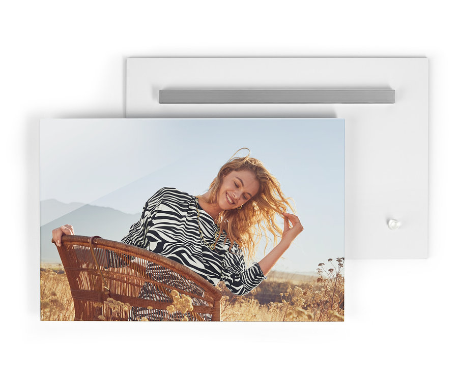 Fotoğrafta, zebra desenli midi elbise giymiş, omuz çantası, »Pırıltılı Afrika« kolye ve küpeleriyle hasır bir sandalyede oturan bir kadın görülüyor.