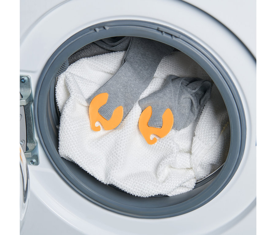 Çamaşır makinesinde bir havlu ve 20 adet çorap klipsiyle tutturulmuş iki çift gri çorap bulunmaktadır.