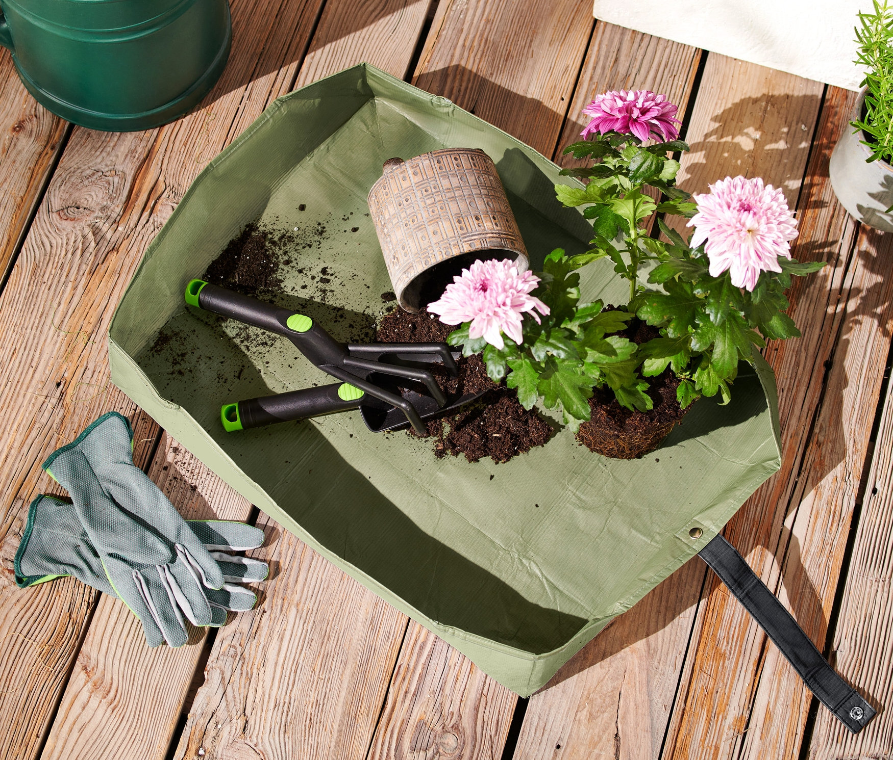 Bitki matı, çiçekler ve ahşap masa üzerinde bahçe aletleri.