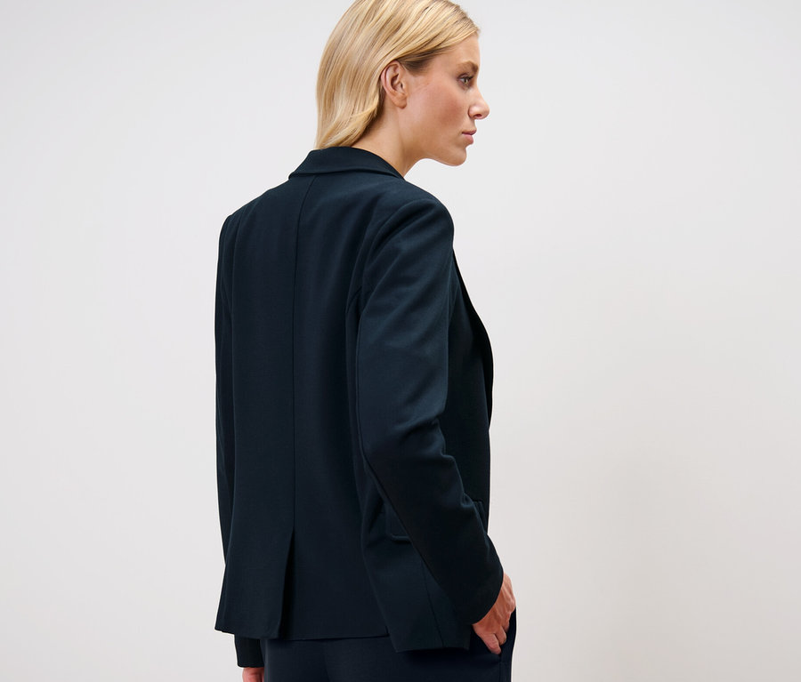 Sarışın bir kadın jersey blazer ceket giyiyor.