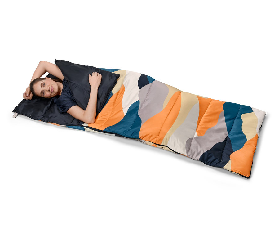 Kadın renkli desenli 4'ü 1 arada yorgan uyku tulumunda yatıyor.