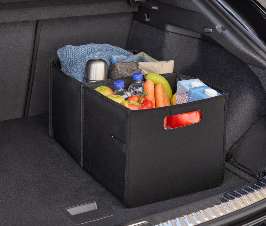 Bir arabanın bagajında yiyecek, su şişeleri, meyve ve sebzelerle dolu siyah bir düzenleyici bulunmaktadır.