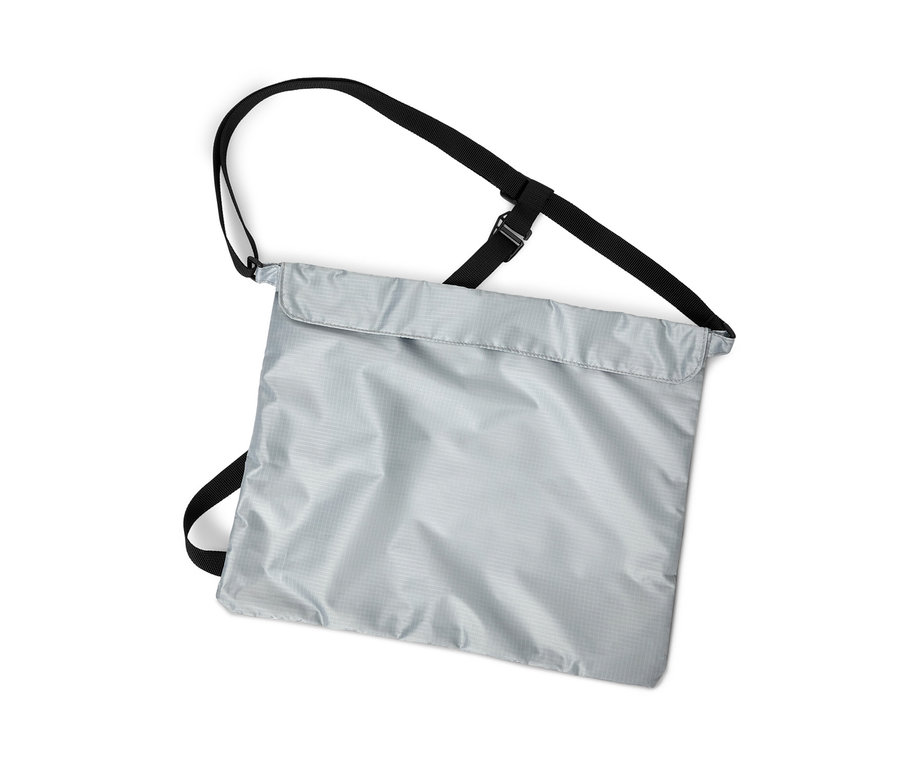 Beyaz arka plan üzerinde siyah askıları olan gümüş rengi bir bisiklet alışveriş çantasının dikey çekimi.