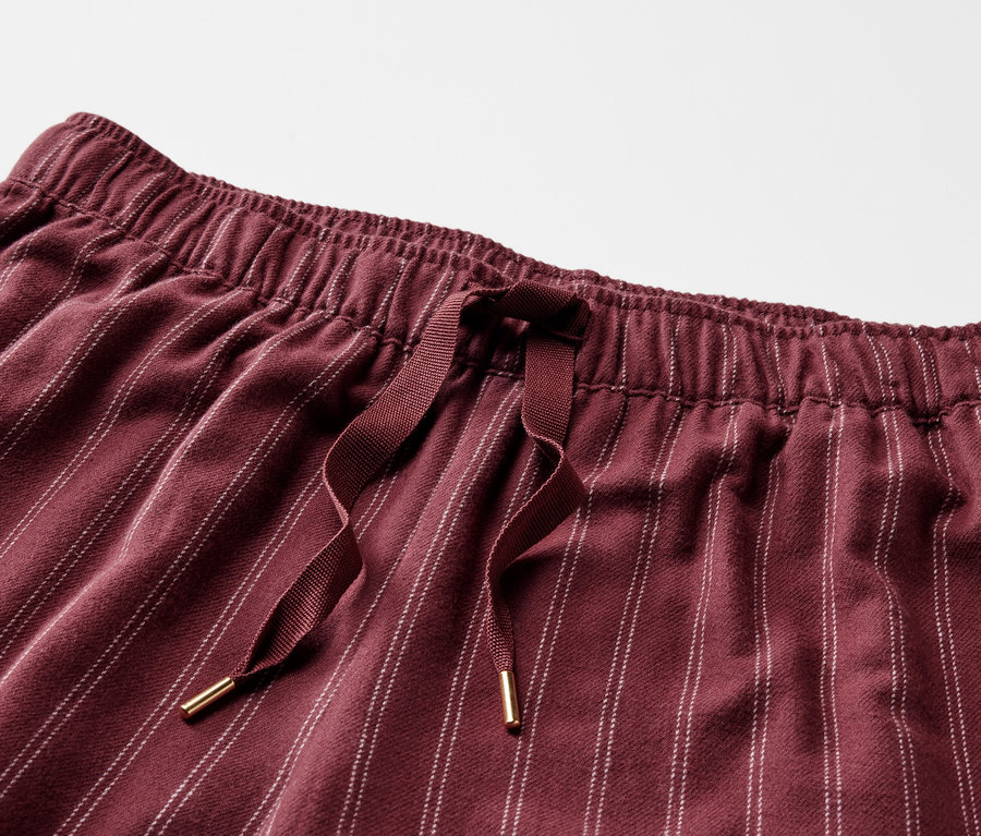 Bordo çizgili, lastikli belli ve bağcıklı bir pantolonun detayı.