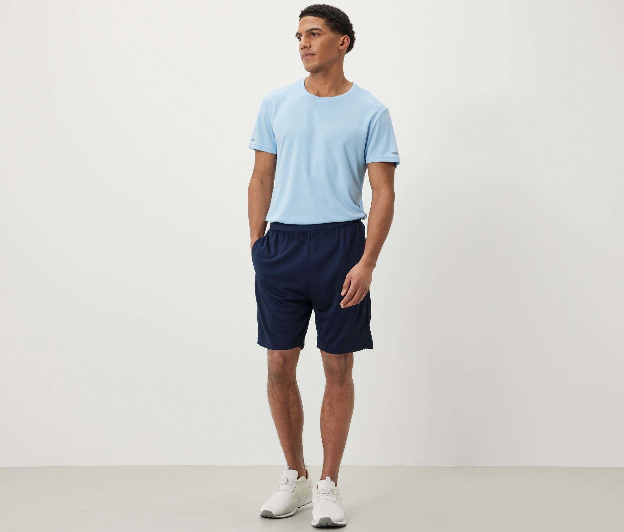 Bir adam spor şortu ve tişört giyiyor.