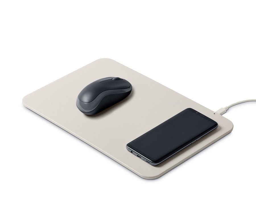 Bir fare, üzerinde bir cep telefonunun durduğu entegre şarj cihazlı bir mouse pad üzerinde duruyor.