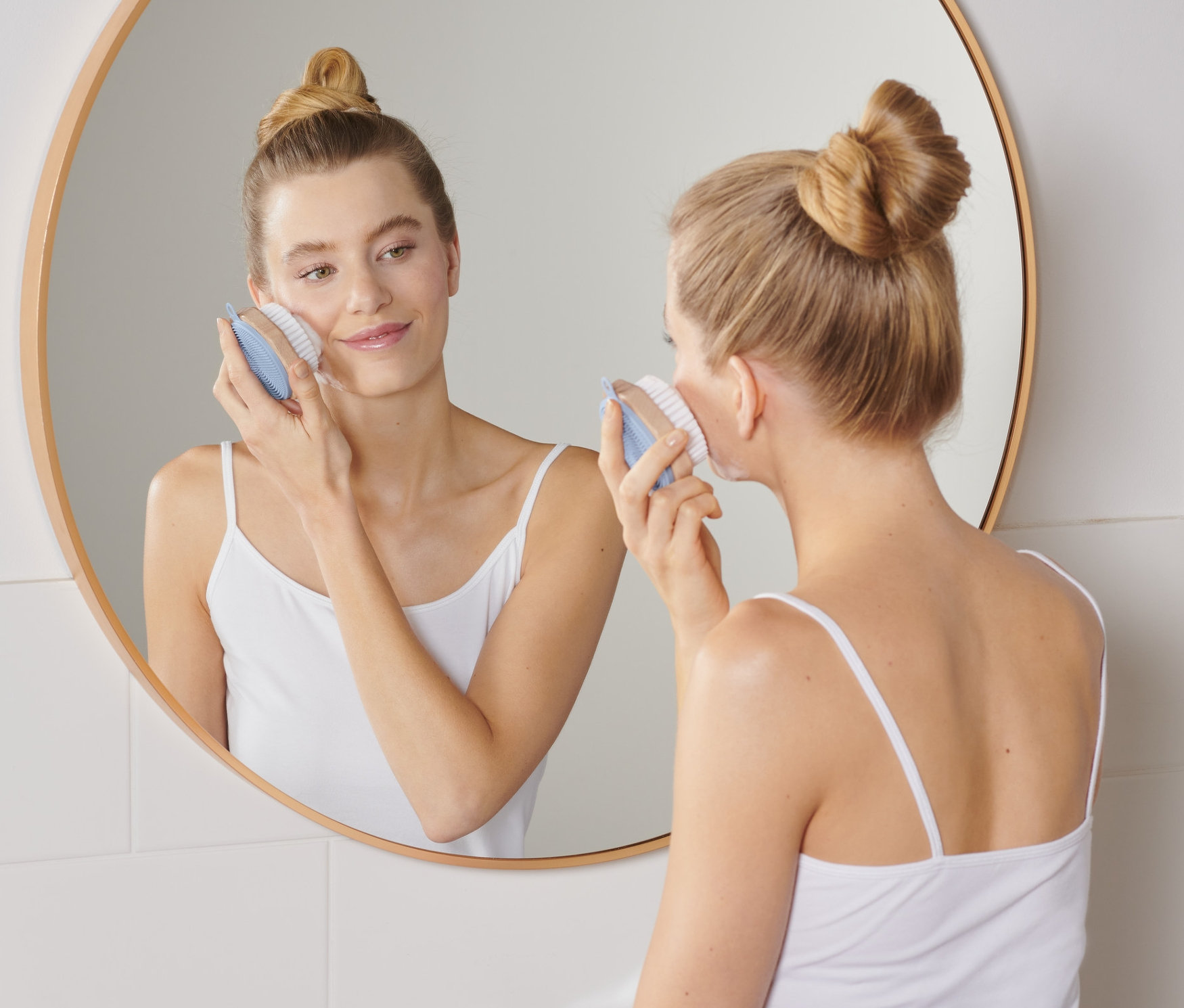 Kadın yüz temizleme fırçası kullanıyor.