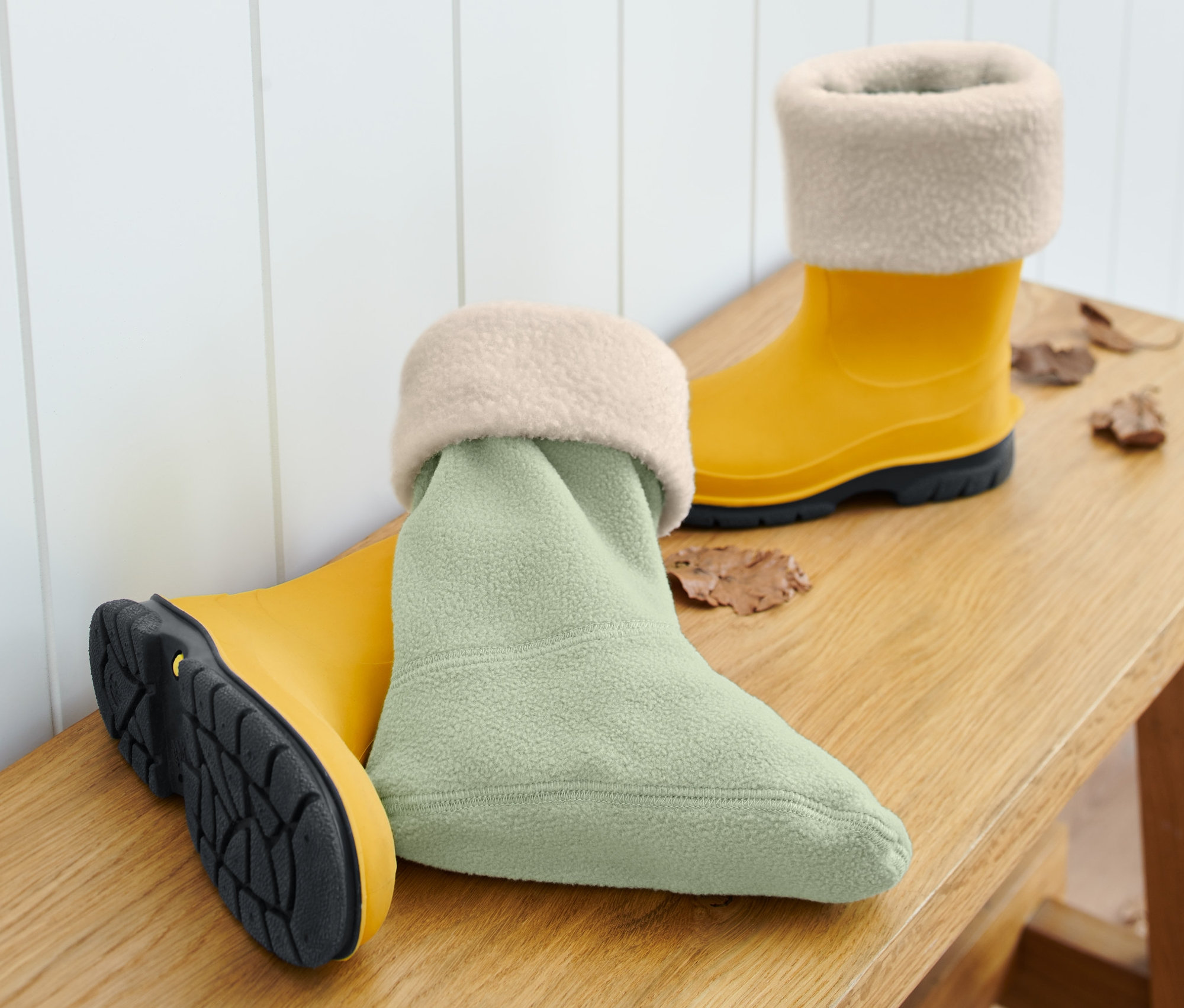 Sarı renkli lastik çizme ve tahta bank üzerinde yağmur çizmesi çorabı.