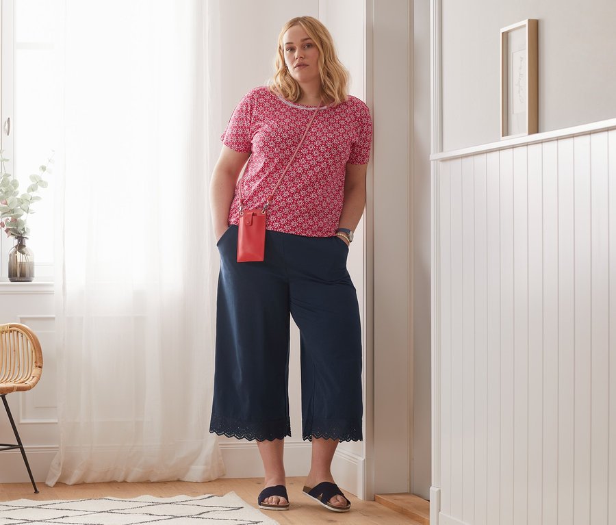 Kadın kırmızı baskılı bluz ve organik pamuklu dantelli culotte pantolon ile poz veriyor.