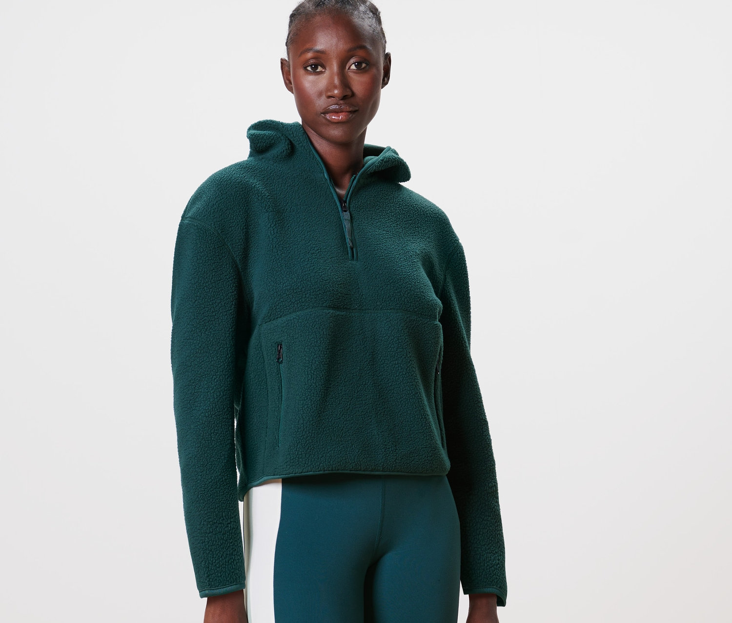 Kadın koyu yeşil kapüşonlu teddy kazak giyiyor.