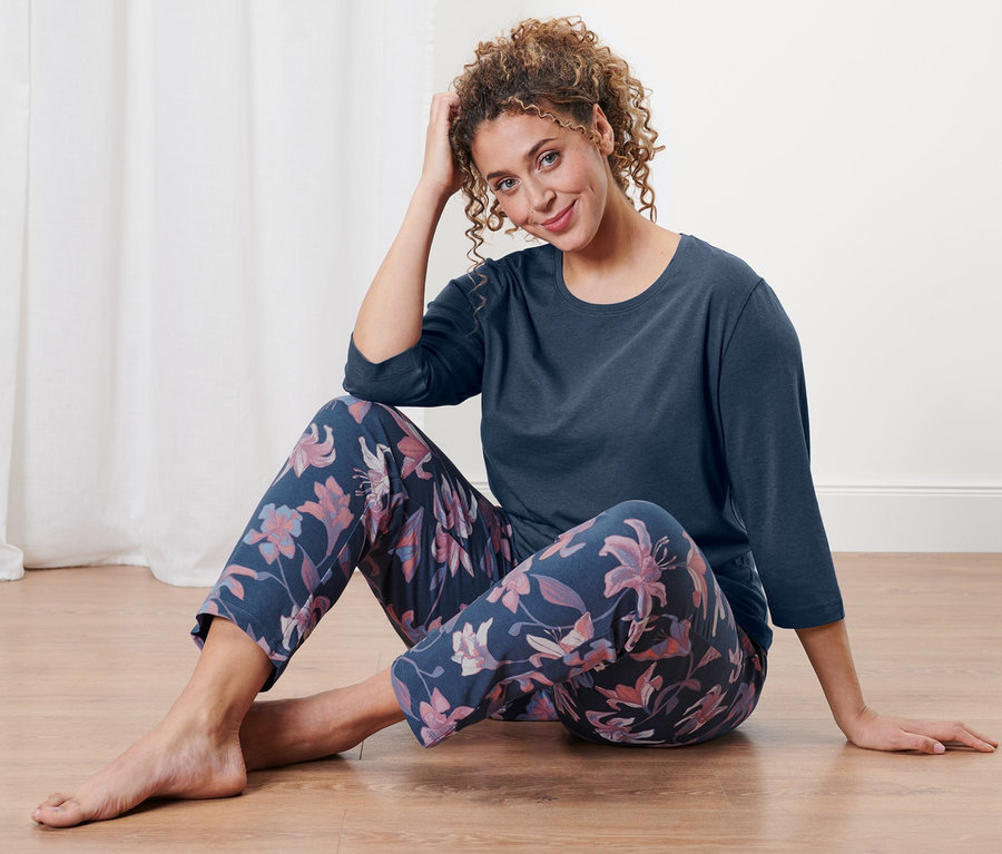 Bir kadın yerde oturuyor ve pijama takımı giyiyor.