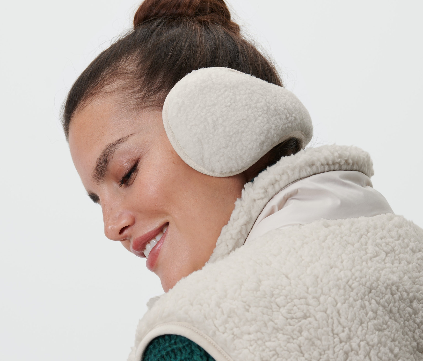 Kahverengi saçlı bir kadın kulak koruyucu takıyor.