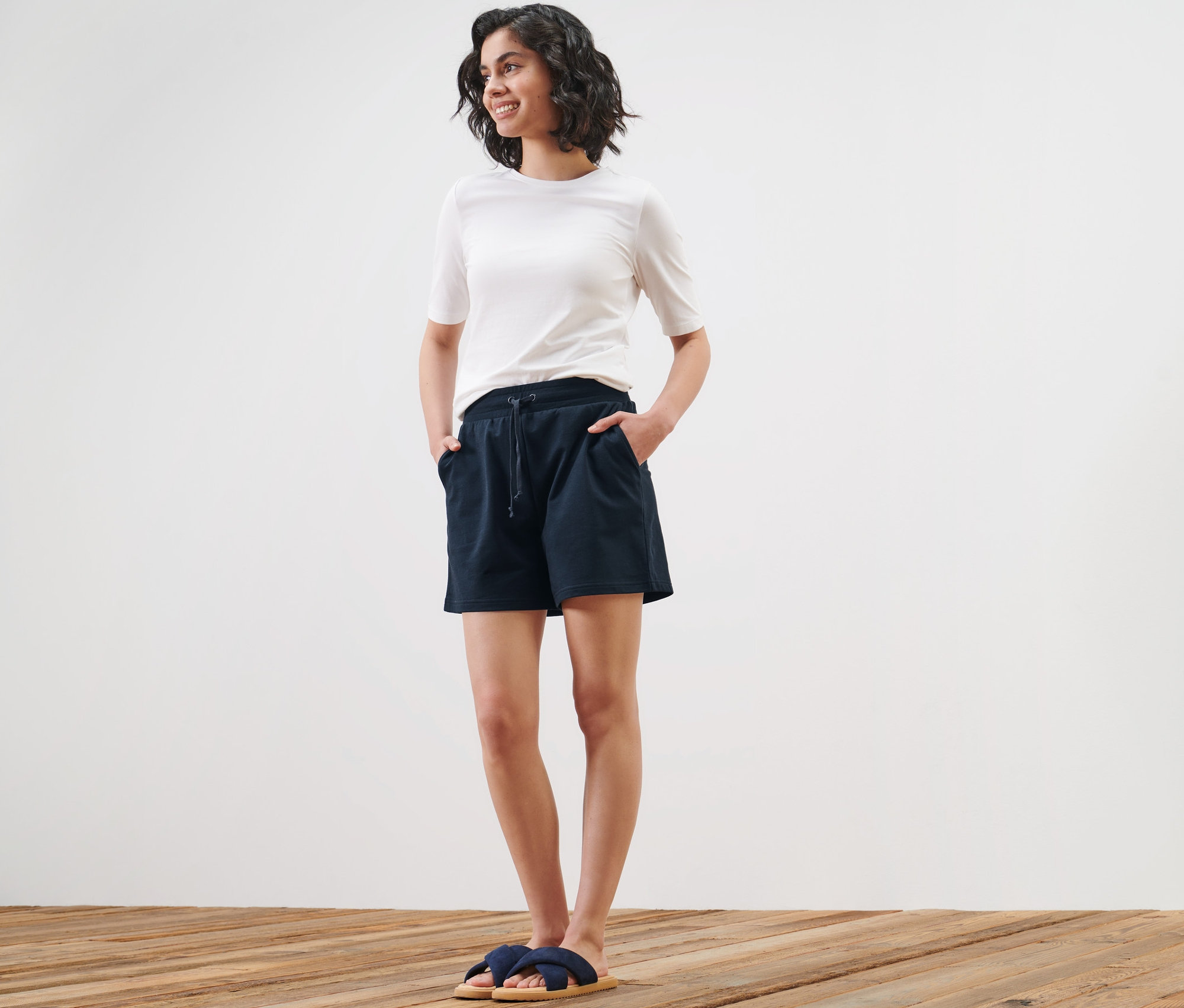 Kadın sweat şort ve tişört ile poz veriyor.