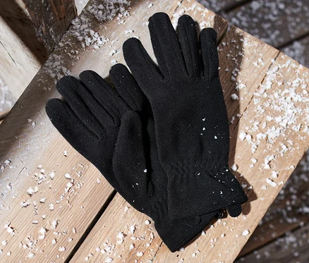 Karla kaplı ahşap bir yüzeyin üzerinde duran siyah mikro polar eldivenler.
