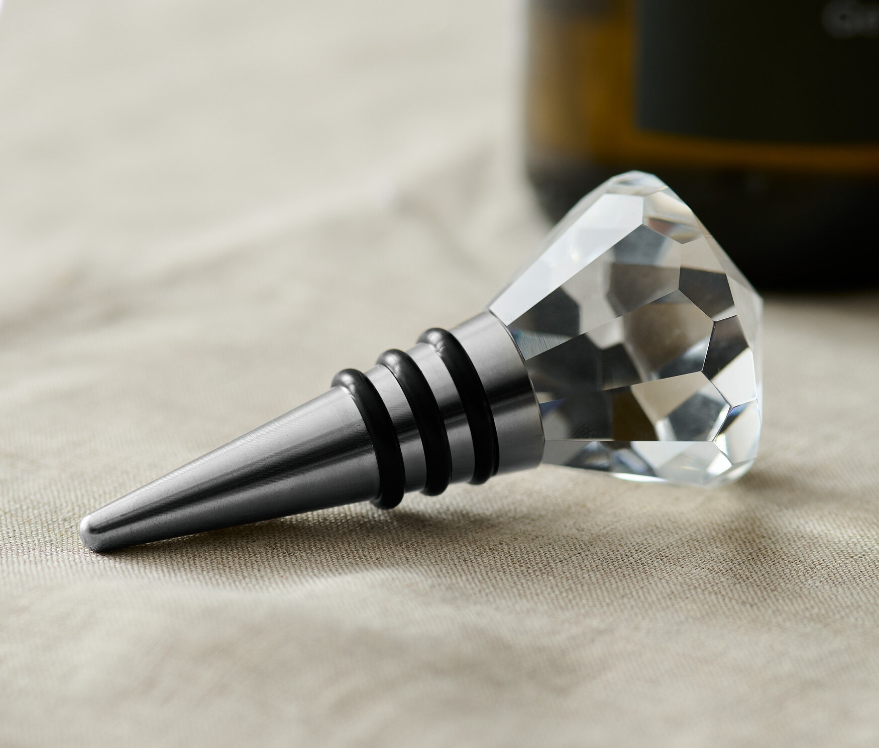 Bej bir örtü üzerinde kristal detaylı bir şişe tıpası duruyor.