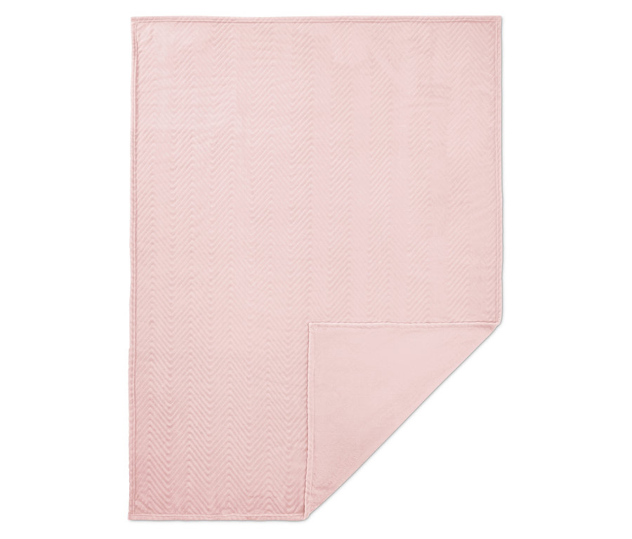 Pembe renkli, kapitone balıksırtı desenli battaniye, alt köşesi kıvrılmış.
