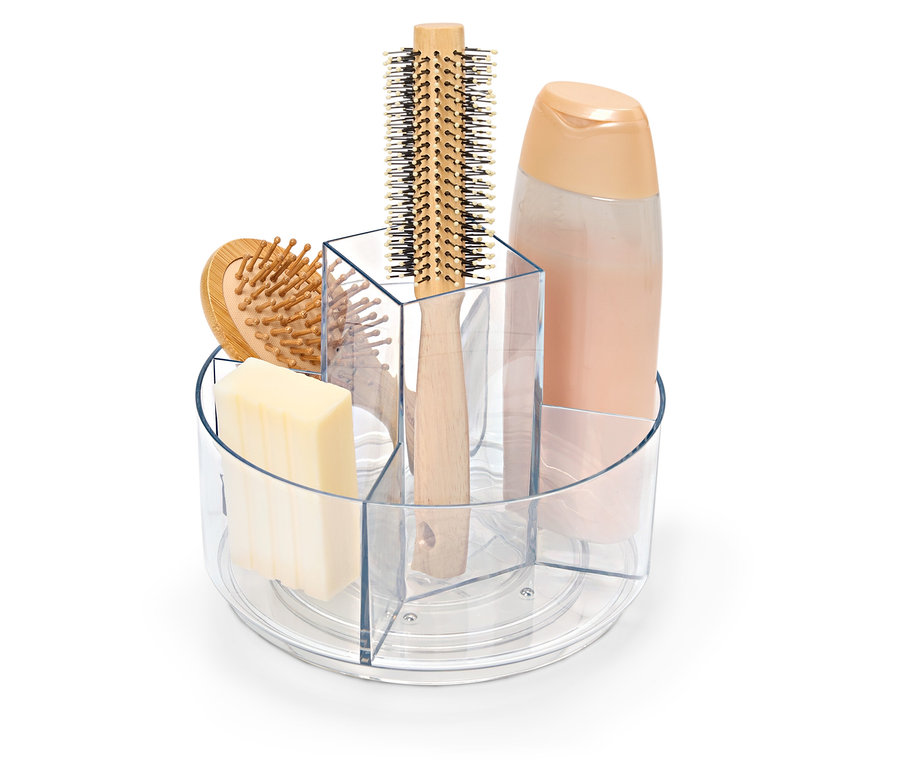 Şeffaf, dönebilen bir kap içinde sabun, saç fırçası ve şampuan şişesi.