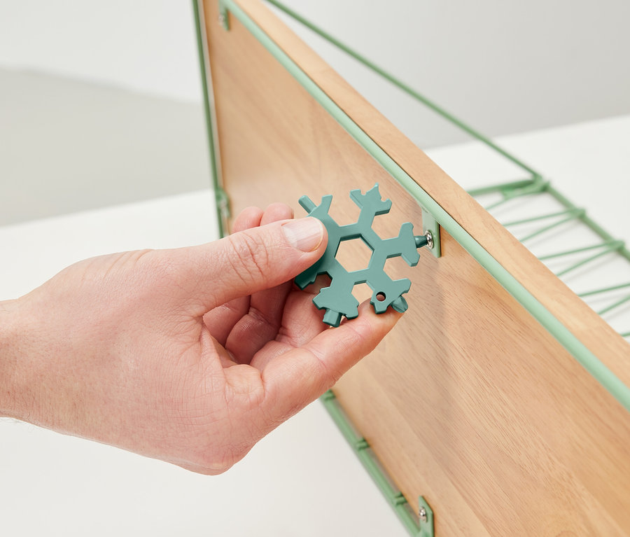 Bir el çok fonksiyonlu bir anahtar tutuyor ve ahşap bir raftaki bir vidayı sıkıyor.