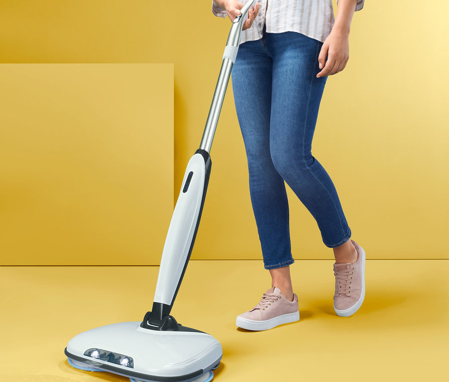 Kadın elektrikli paspas ile zemini temizliyor. 