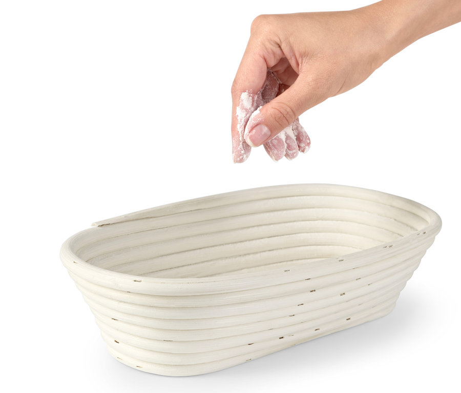 Bir el, oval mayalama sepetine un serpiyor.