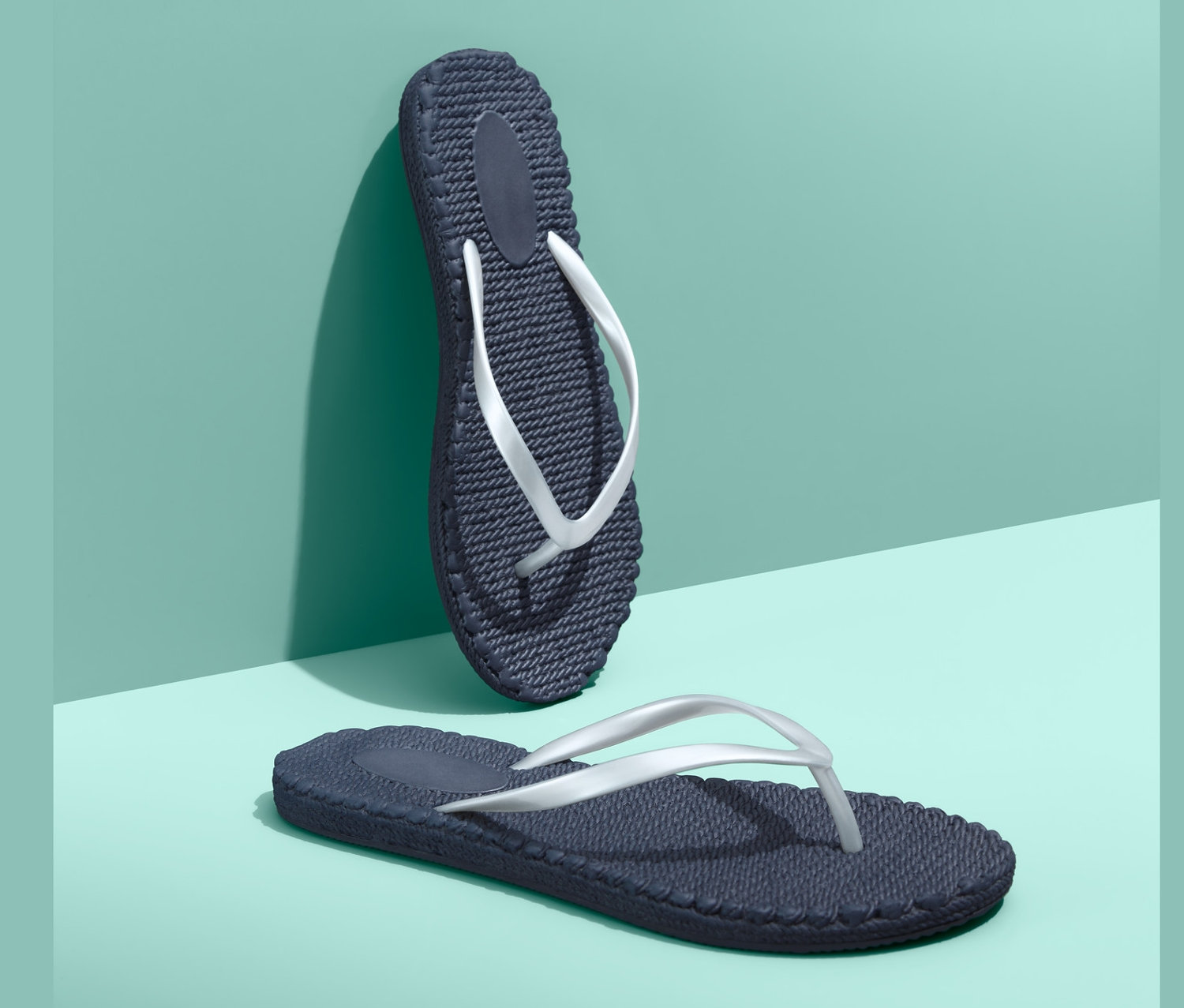 Turkuaz zemin üzerinde iki adet lacivert parmak arası terlik.
