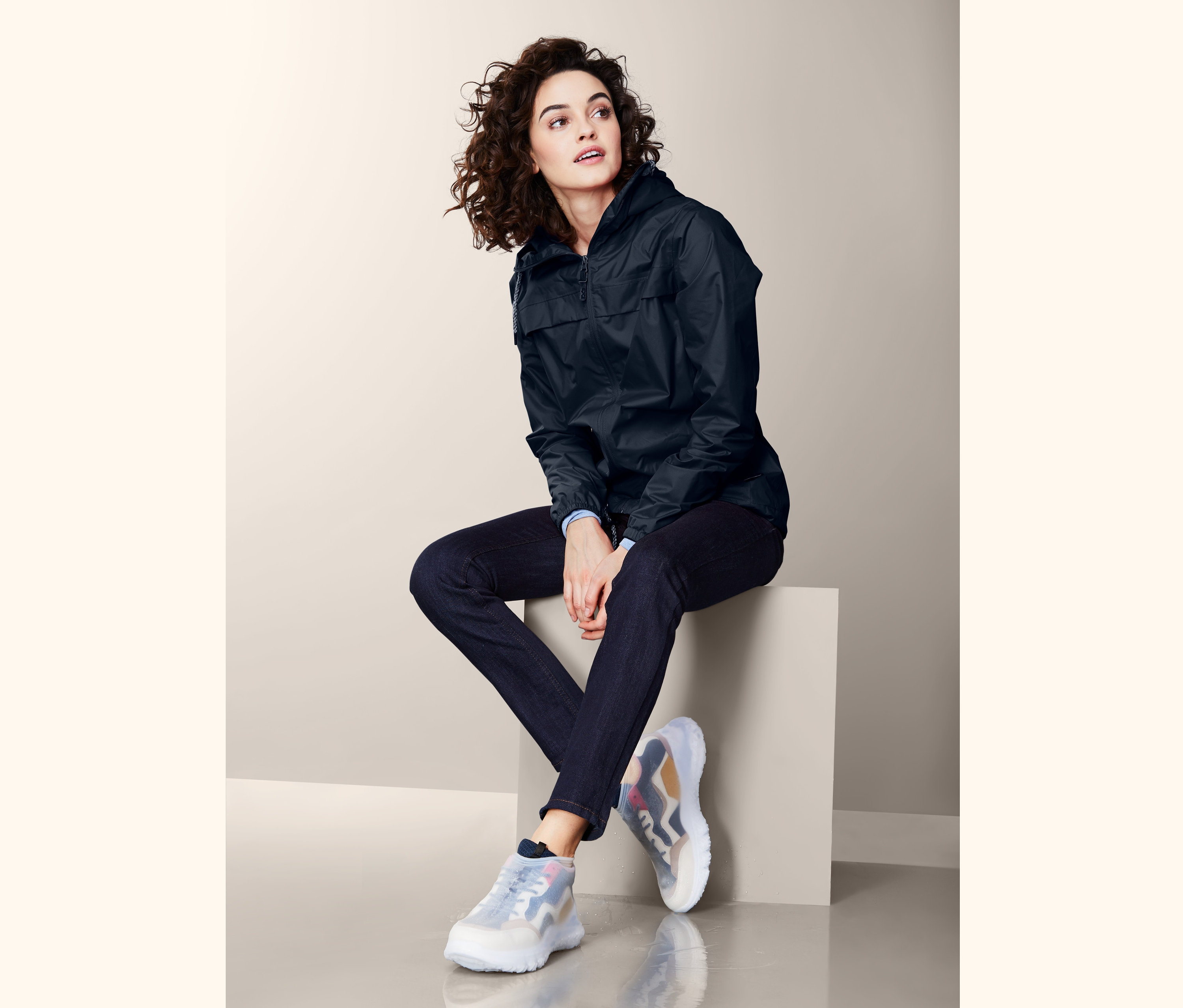 Bir blokta oturan ve Ayakkabı Yağmurluğu giyen kadın.