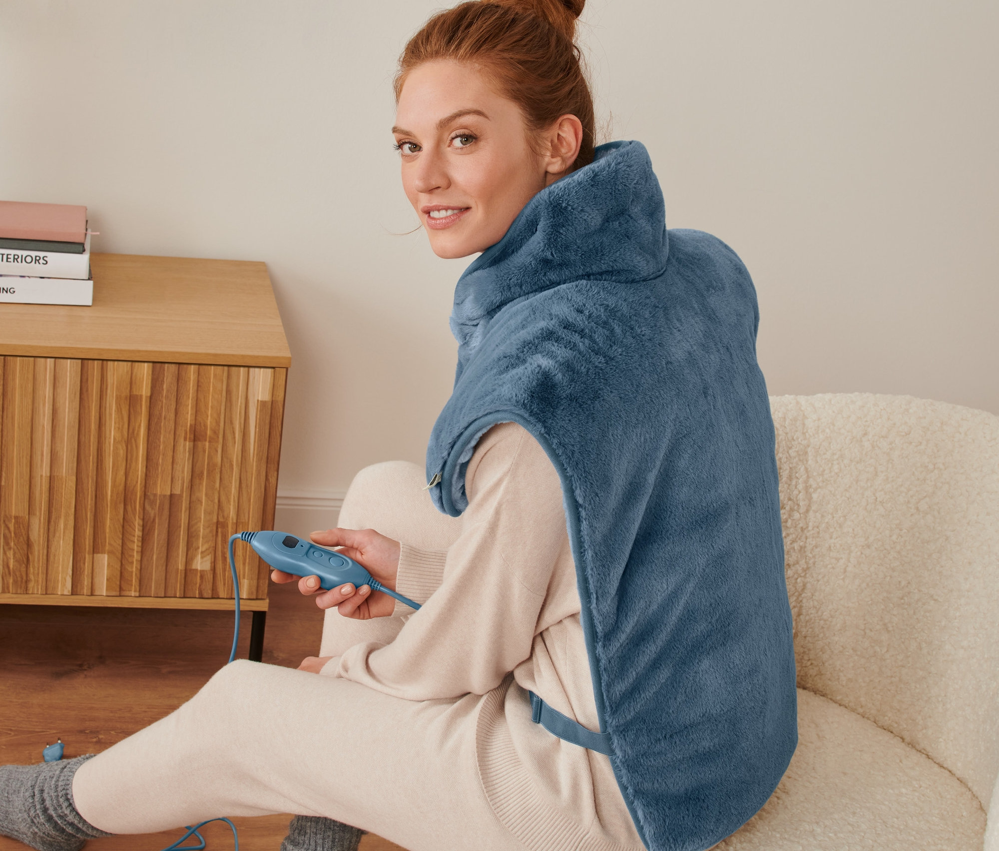 Kadın oturuyor ve Sırt Isıtıcı Yastık takıyor.