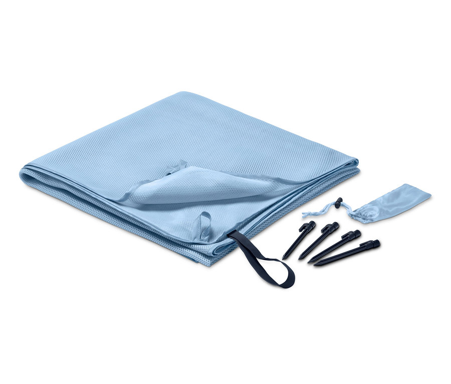 Açık mavi kum tutmayan plaj örtüsü kazıkların ve bir kılıfın yanında katlanmış.