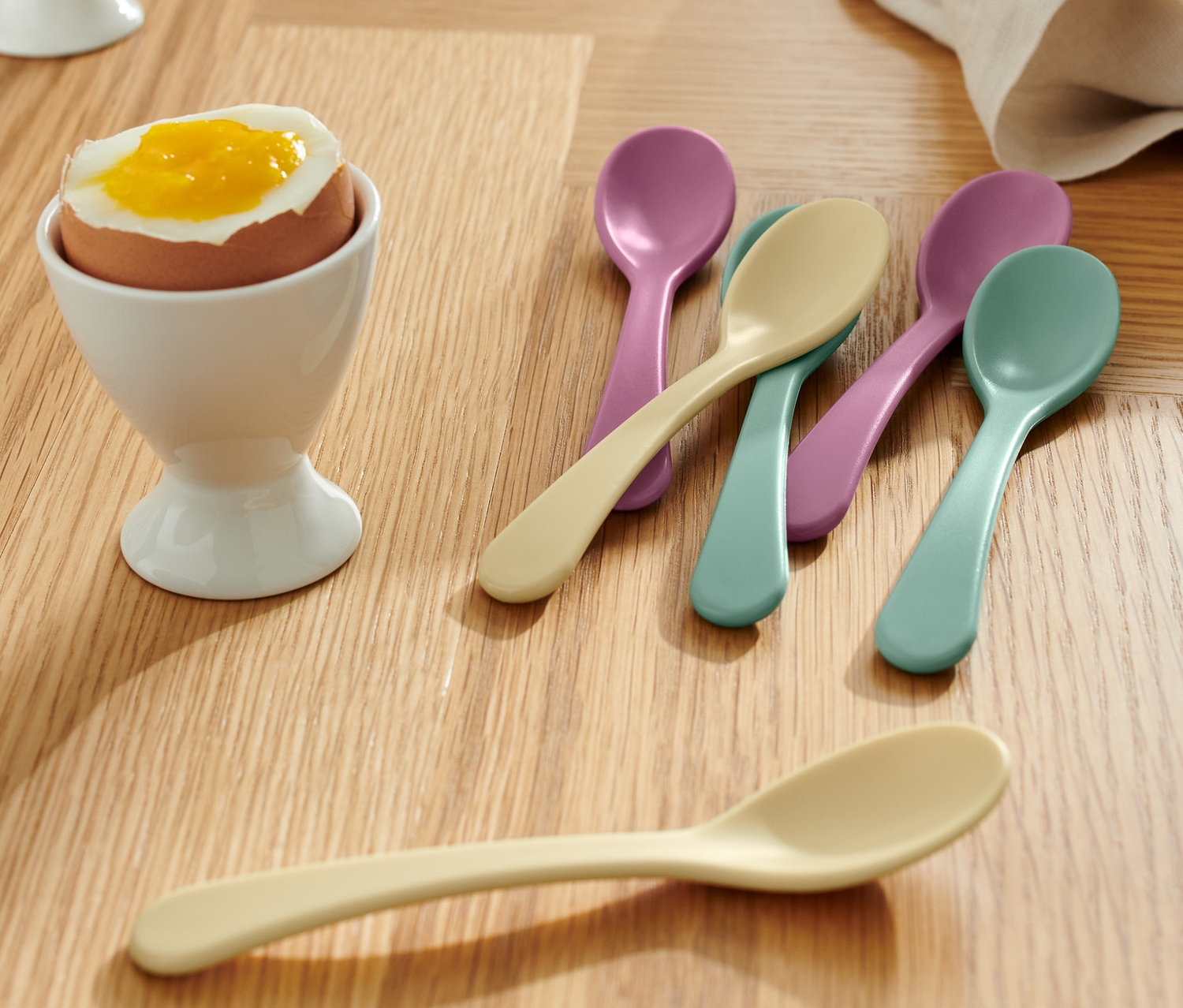 Ahşap bir masanın üzerinde beyaz yumurtalıklarda yumurtalar ve 6 Adet Yumurta Kaşığı görülüyor.