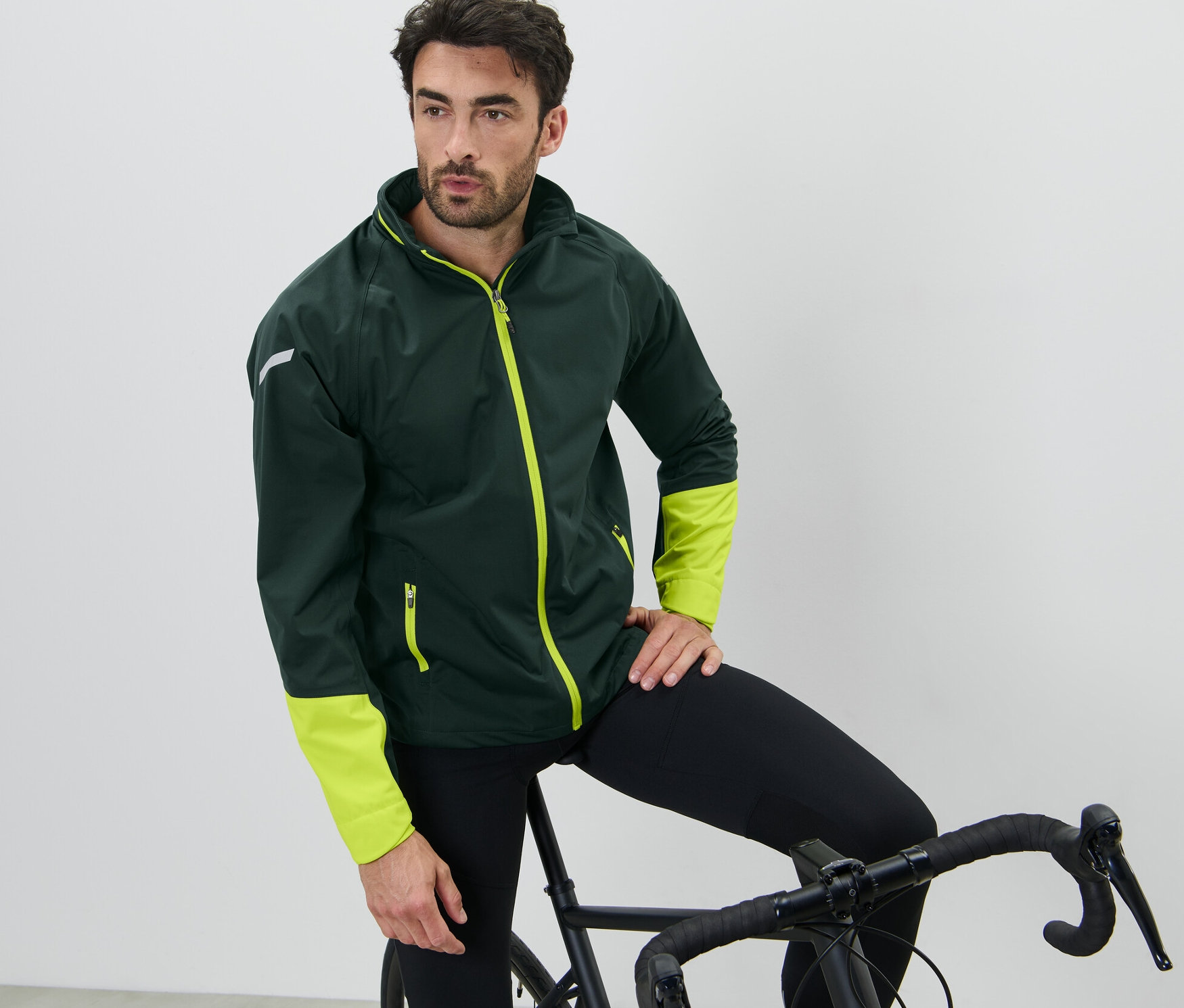 Bisikletine yaslanan adam Bisiklet Yağmurluğu giyiyor.