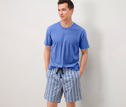 Mavi tişört ve çizgili şortlu Şortlu Pijama giyen adam.