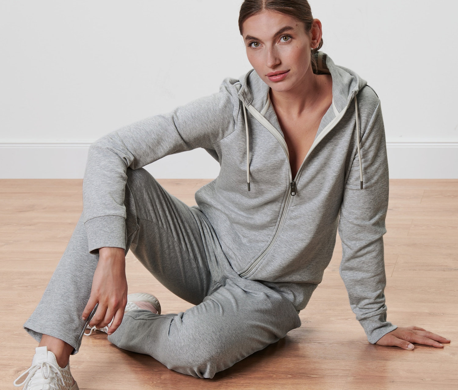 Kadın yerde oturuyor, gri Sweat Ceket giyiyor.