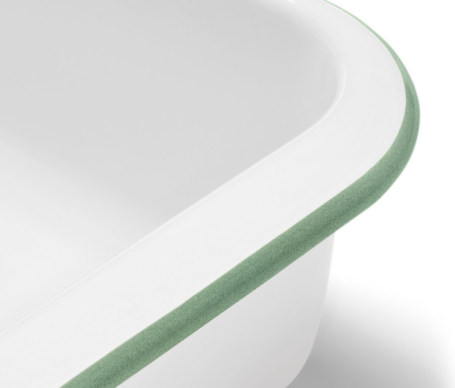 Yeşil kenarlı, kapaklı beyaz emaye fırın kabının yakın çekimi.