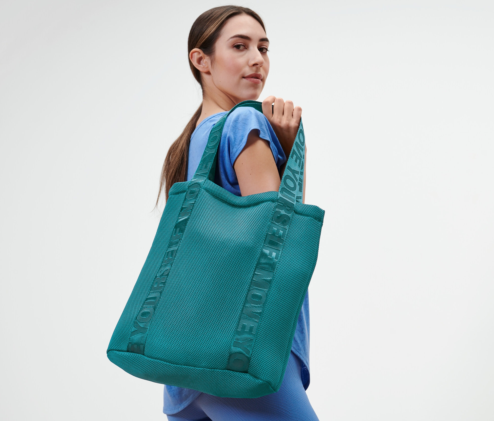 Kadın spor çantasıyla poz veriyor.