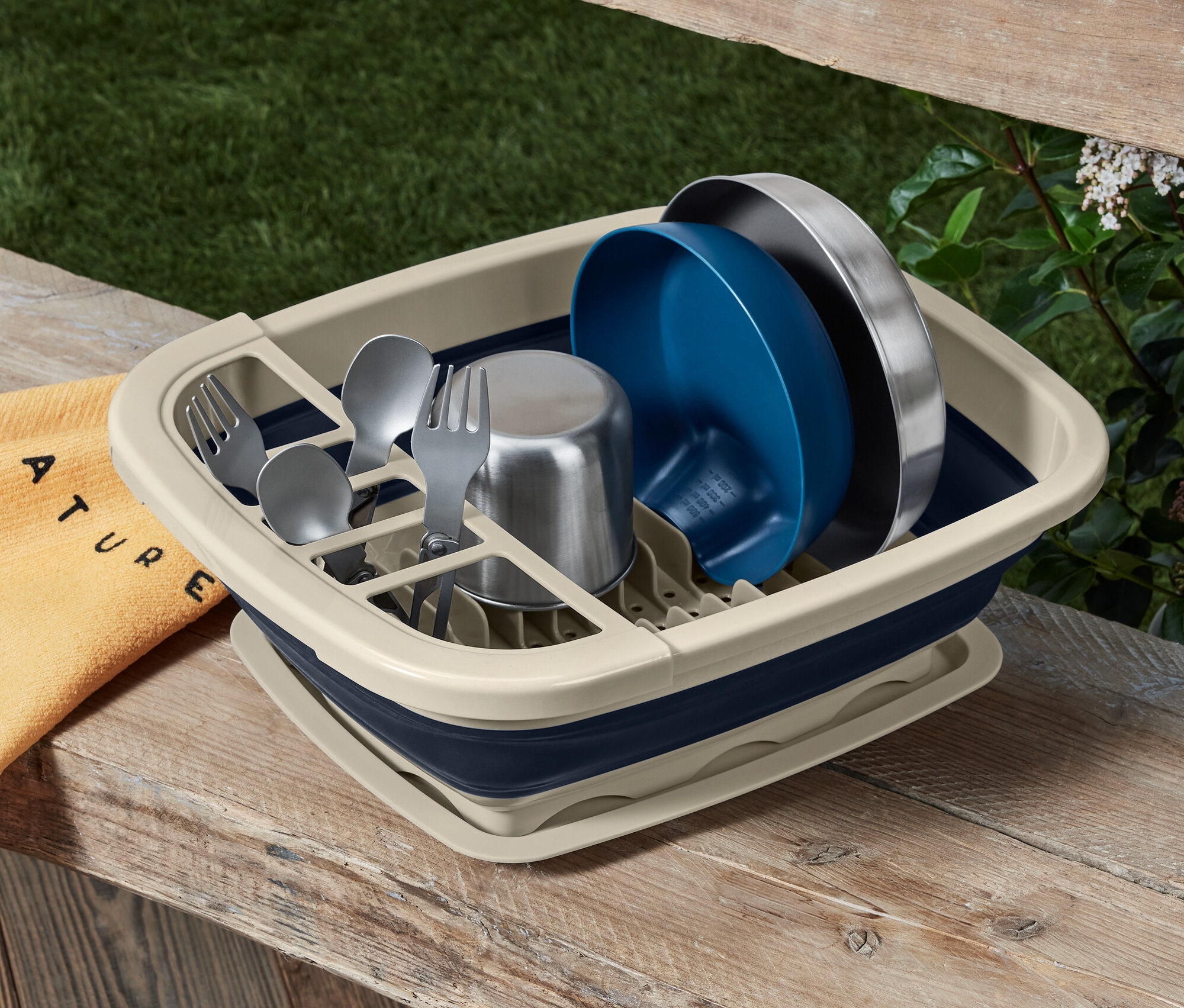 Ahşap bir masa üzerinde bulaşık ve çatal bıçak takımı bulunan katlanabilir bulaşıklık.