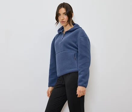 Kadın mavi kapüşonlu polar sweatshirt ve siyah pantolonla poz veriyor.