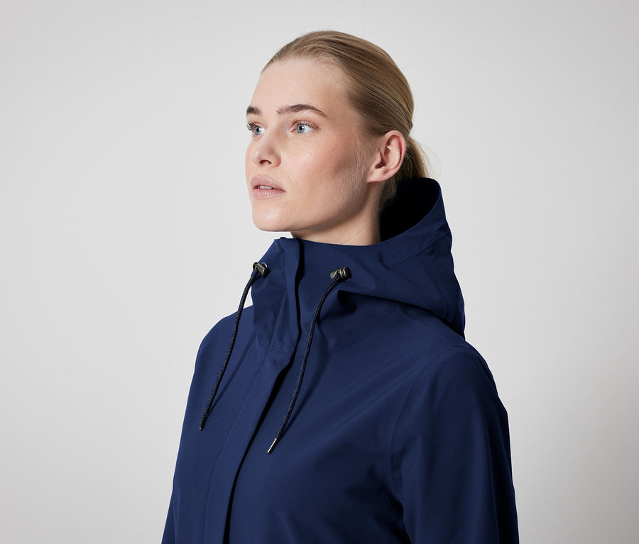 Bir kadın kapüşonlu koyu mavi bir ceket giyiyor.