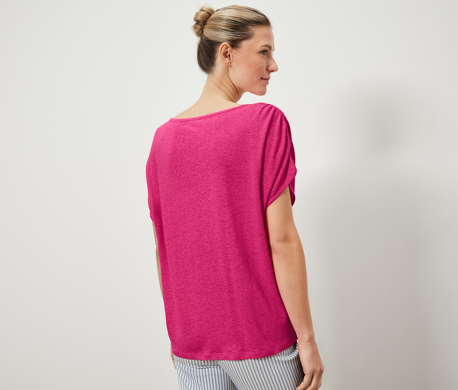 Kadın keten karışımlı bir tişört ve çizgili bir pantolon giyiyor.