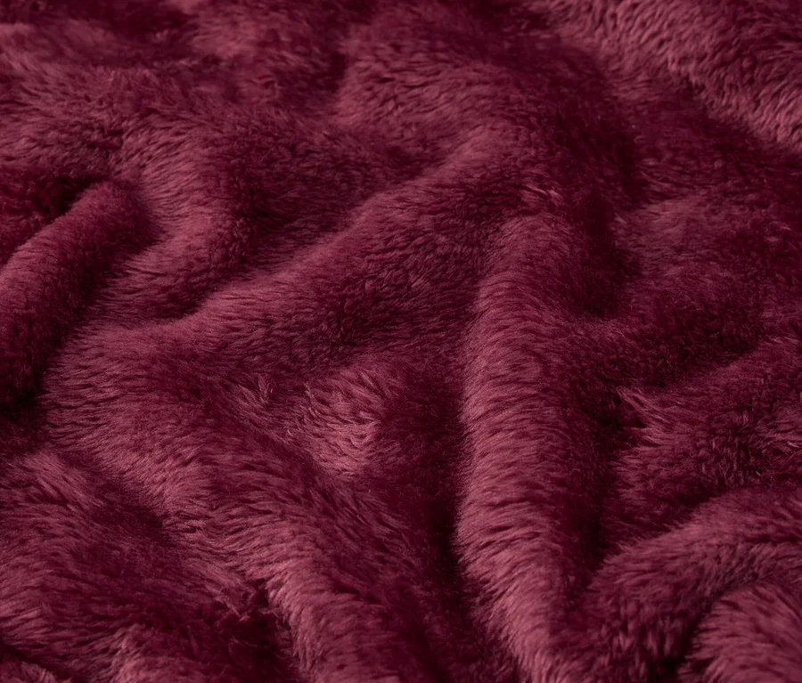 Kıvrımlı, bordo renkli peluş kumaşın yakın çekimi.