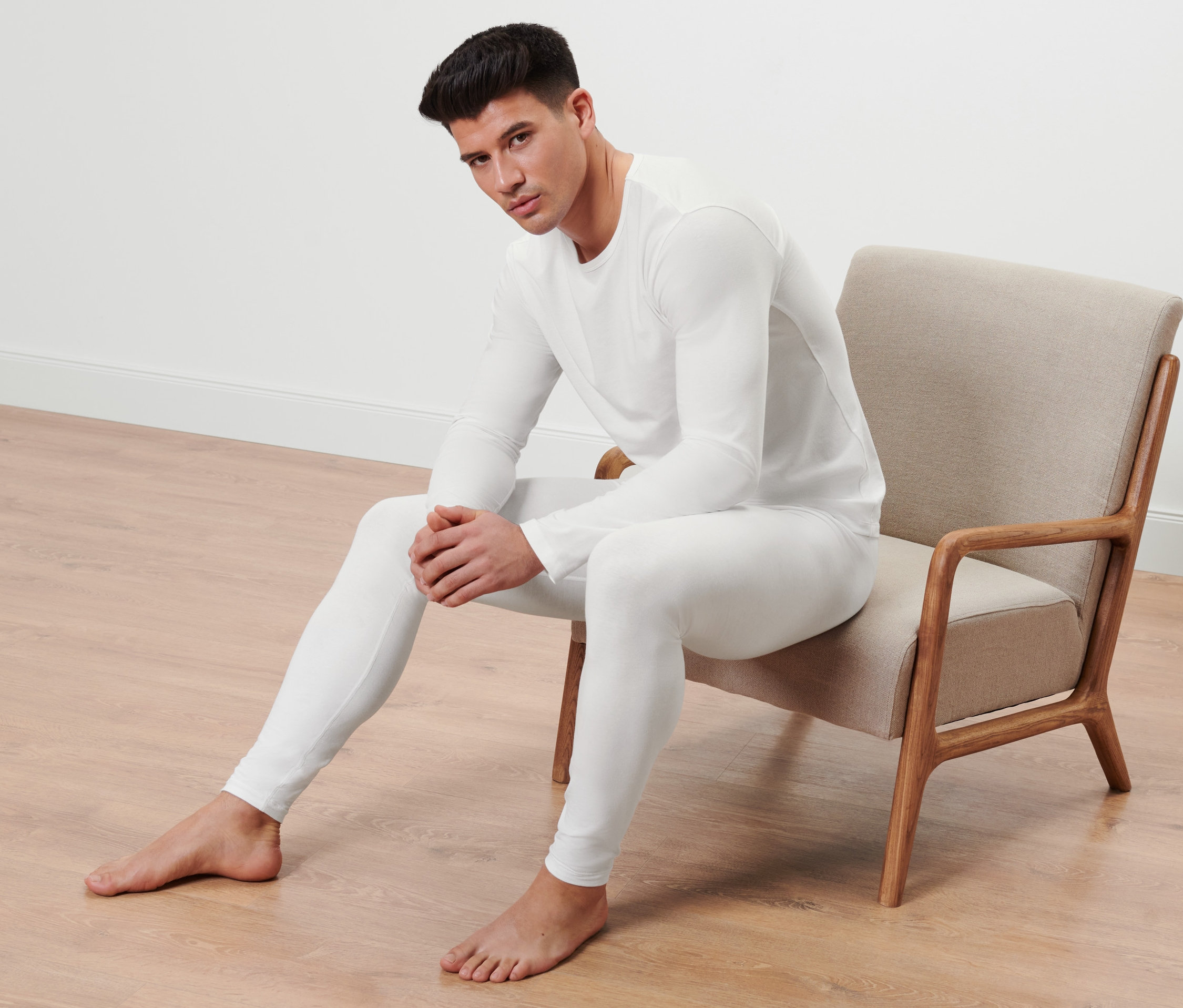 Bir adam sandalyede oturuyor ve 2 Adet Uzun Kollu İçlik giyiyor.