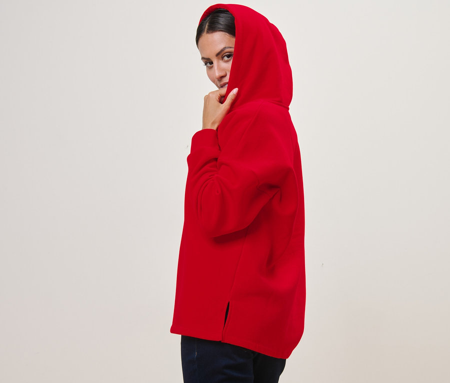 Kırmızı kapüşonlu sweatshirt giyen bir kadın poz veriyor.