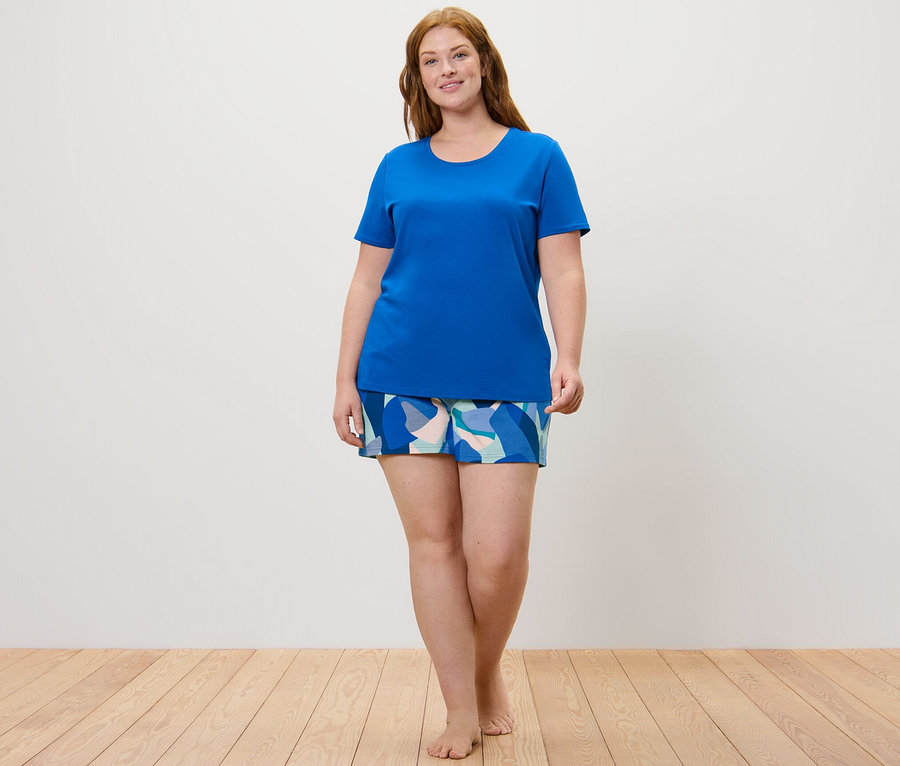 Kadın şortlu pijama takımı giyiyor.