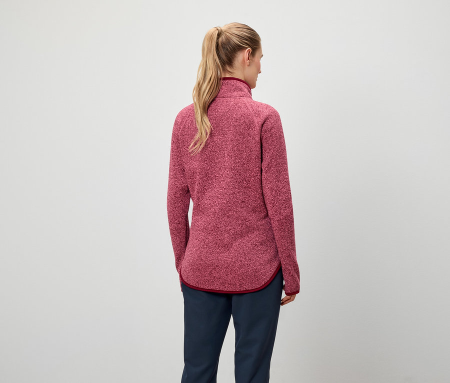 Arkadan at kuyruğu yapılmış sarı saçlı, kırmızı sweatshirt ve lacivert pantolonlu bir kadın görülüyor.