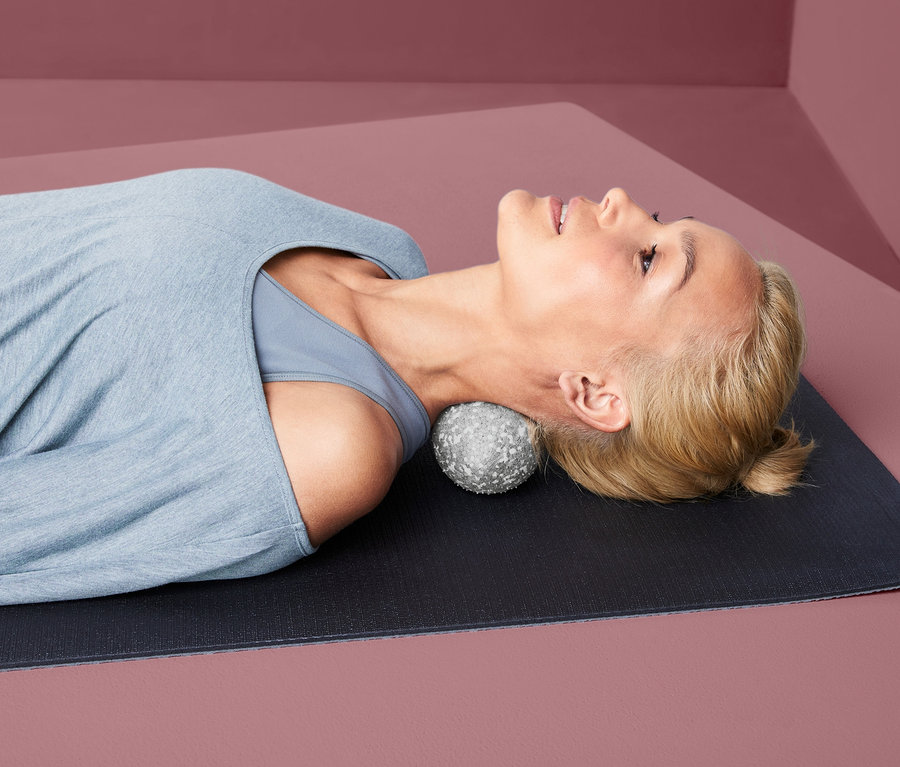 Kadın yerde yatıyor, başı İkili Bağ Doku Masaj Topunun üzerinde.