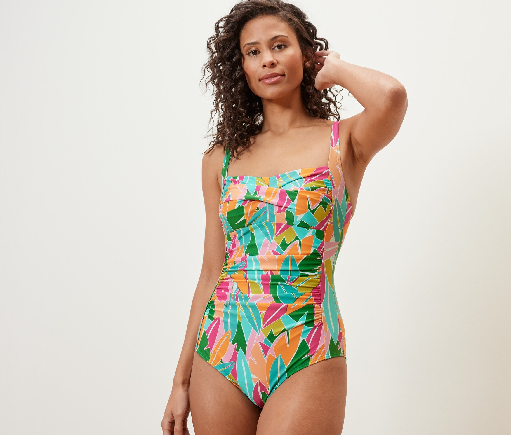 Kadın çok renkli, şekillendirici mayoyla poz veriyor.