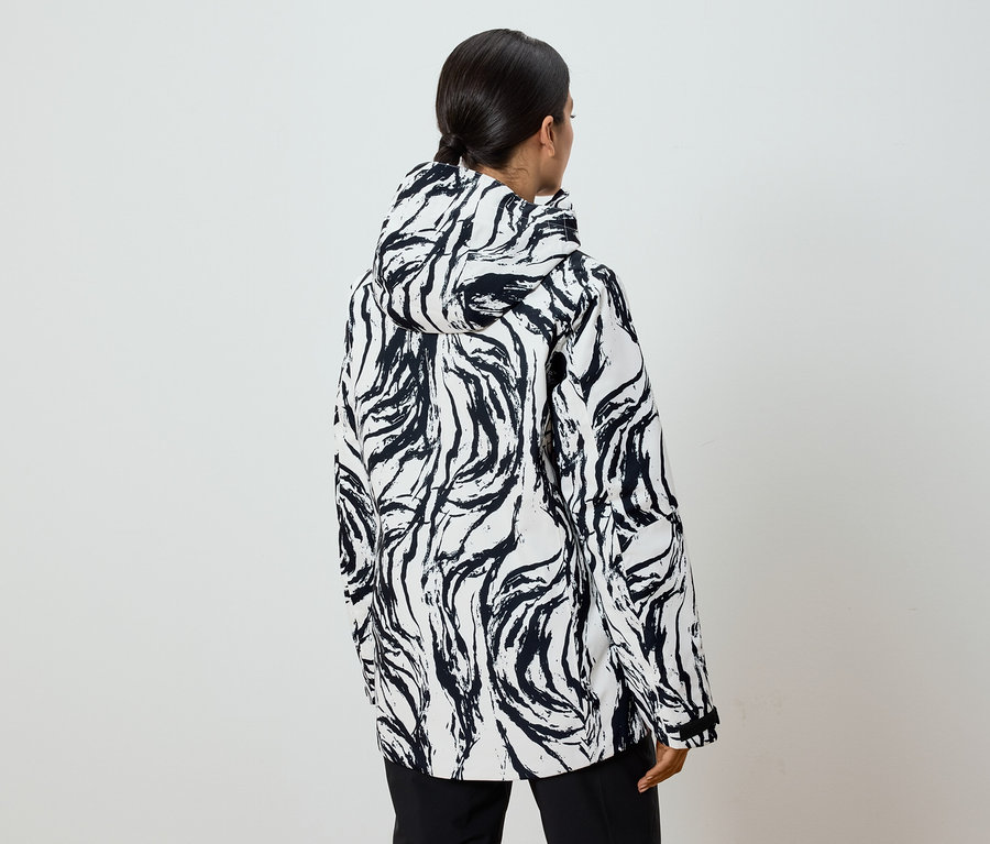 Atkuyruklu, siyah beyaz desenli kapüşonlu bir ceket giyen bir kadının arka görünümü.