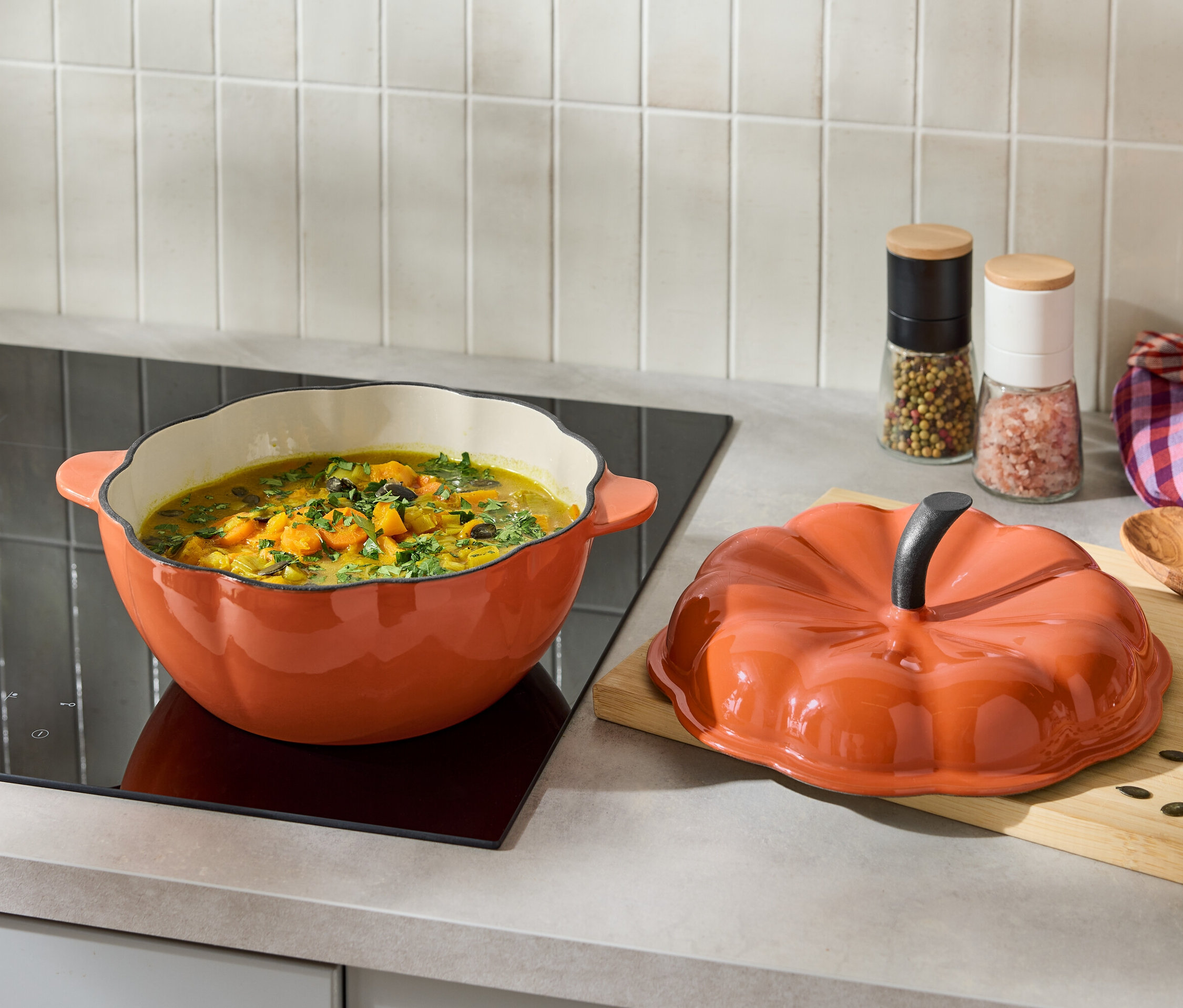 İndüksiyonlu ocakta balkabağı şeklinde turuncu kapaklı turuncu tencere içinde çorba var.