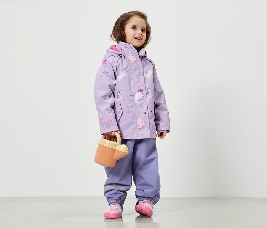 Lilac renkli, tek boynuzlu at desenli yağmurluk giyen bir kız çocuğu sulama kabı tutuyor.