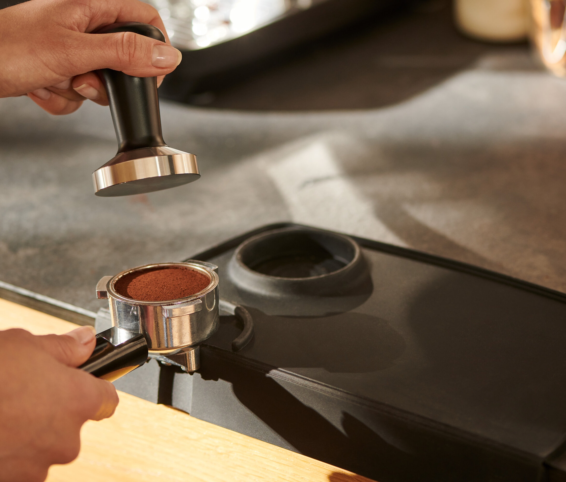 Bir el, siyah bir tamper'ı bir tamper matının üzerinde tutuyor.