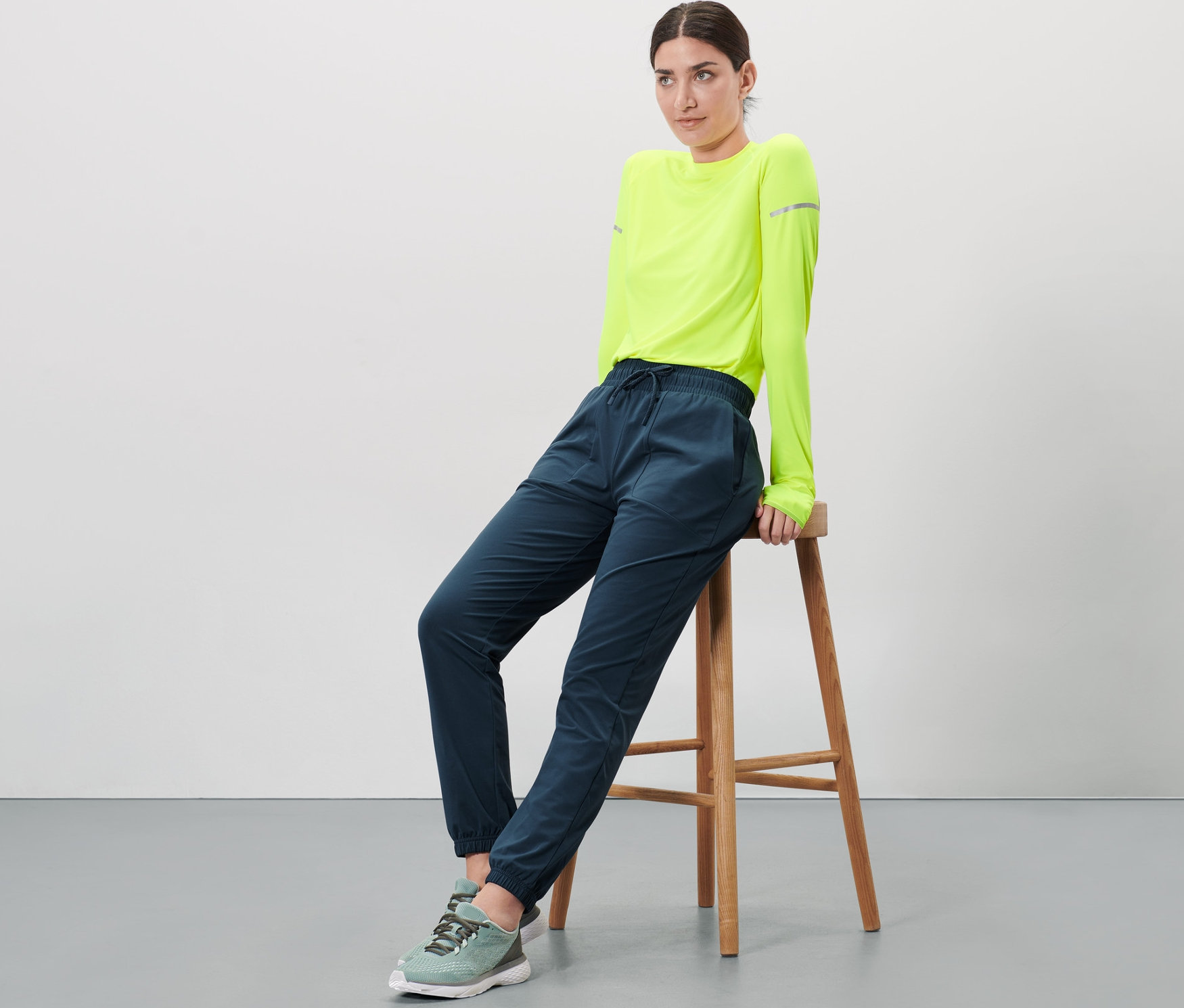 Kadın bir taburede oturuyor ve termal pantolon giyiyor.